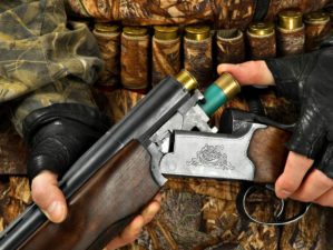 Hands of hunter in camouflage loading the double-barreled shotgun for shooting | Best Shotgun Reloading Techniques | Featured