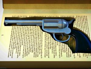 Featured | A hardback book with a cutaway area in the pages concealing a metal pistol on an isolated background | Gun Storage Solutions: How To Hide Your Guns