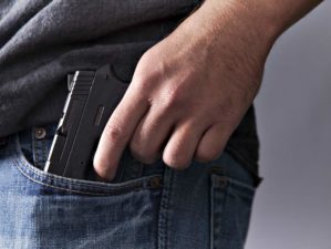 A man legally carries a firearm in his pocket for protection close up | Concealed Carry Tips | Traveling With A Gun | Featured