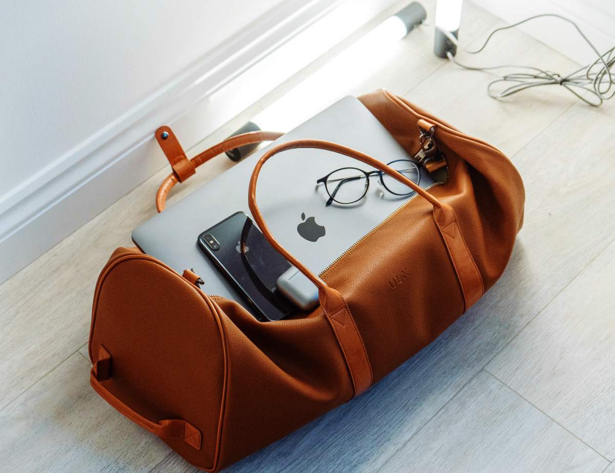 A silver MacBook and mobile phone in duffel bag preparedness us