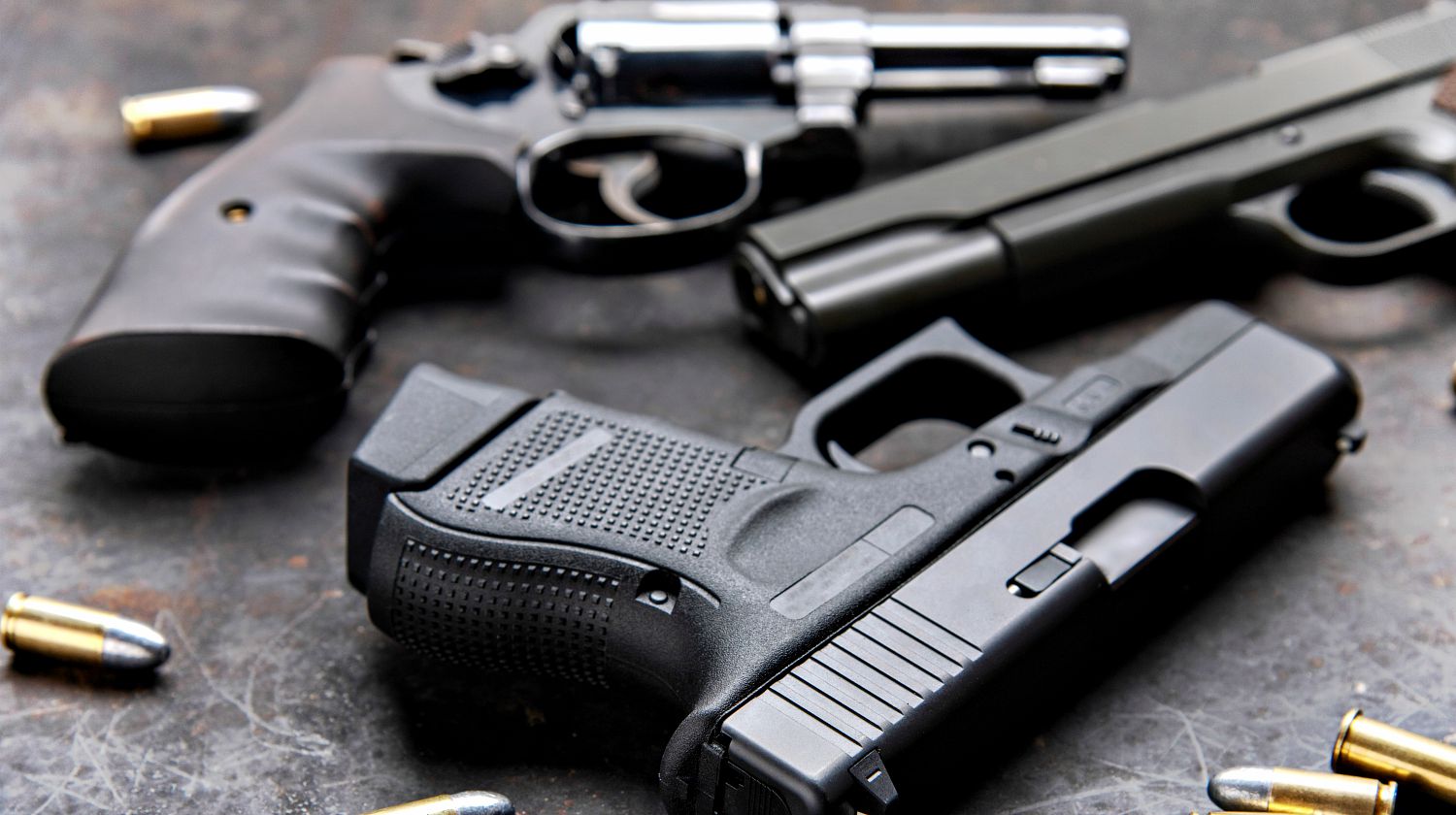 Gun, pistol with ammunition on wooden background | A 'Complete' List of Handgun Calibers | Featured