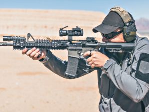 Man with gray jacket shooting black rifle on range in desert | How To Protect Your Hearing When Shooting | Featured