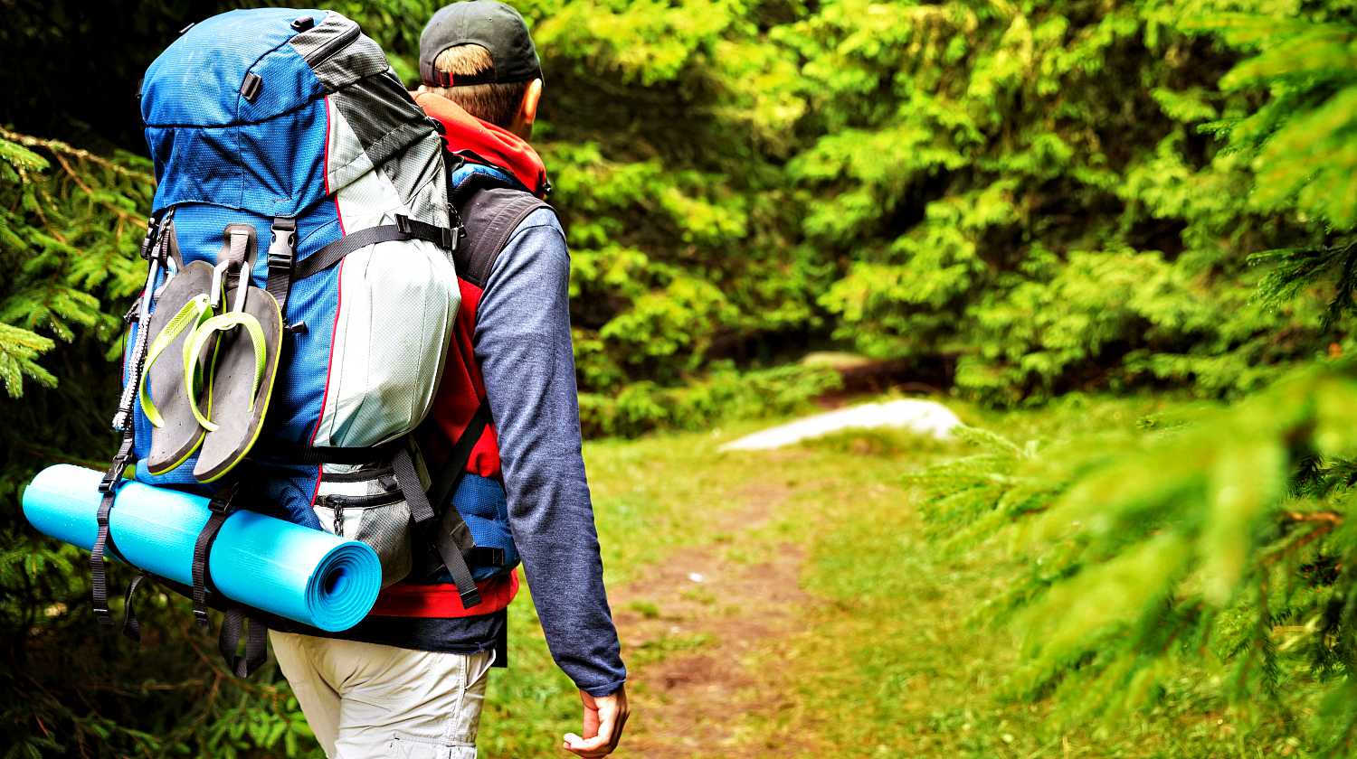 Featured | Male backpacker hiking/tracking through mountain forest | Preparing Your INCH Bag