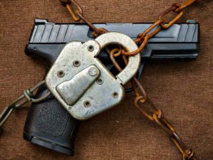 Featured | Pistol behind Lock and Chain | Gun Control | Guns The Government Will Ban First