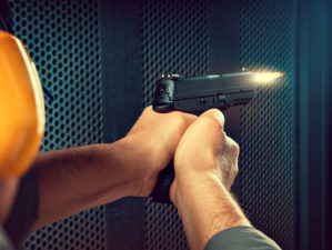 A man firing pistol at target indoor shooting range | Pistol Shooting Tips: Introduction To One-Handed Pistol Shooting | Featured