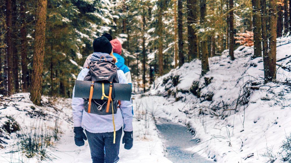 Feature | two people walking in woods with snow | Winter Survival Gear: Winterizing Your Bug Out Bag | winter survival food