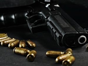 Handgun with ammunition on a black surface, photographed on low light | Mistakes New Gun Owners Make And How To Avoid Them | Featured