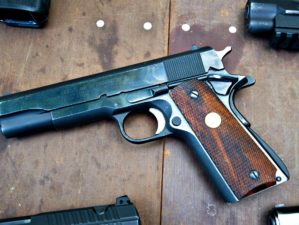 Feature | Black pistols on a wooden table | Colt Defender Series | Gun Carrier Compact Pistol Review
