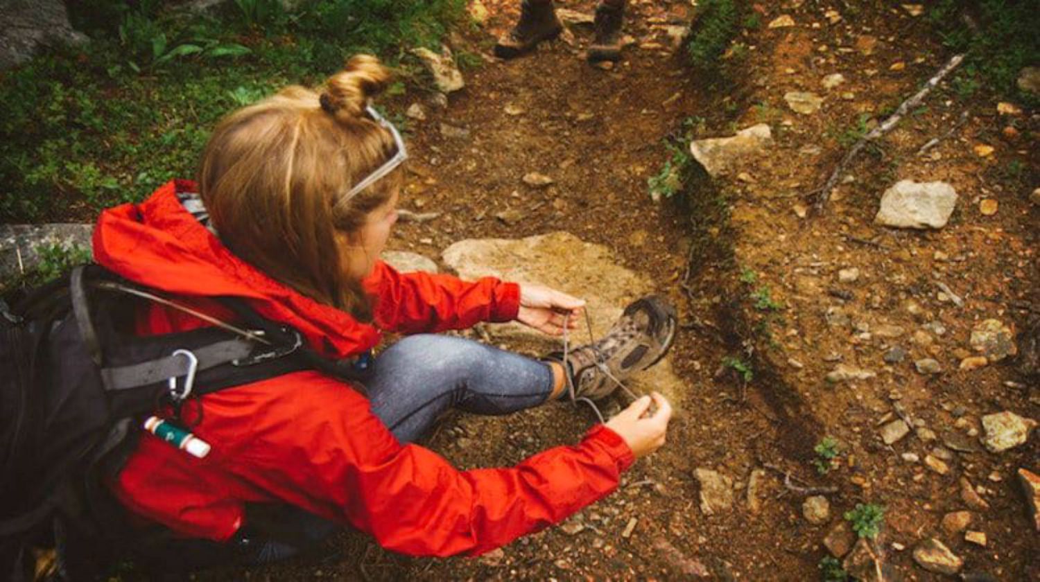 Feature | Woman tying hiking boots | Common Prepper Mistakes