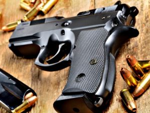 Feature | 9mm pistol, bullets and magazine on old wooden table | Handgun Reviews: The Taurus PT92