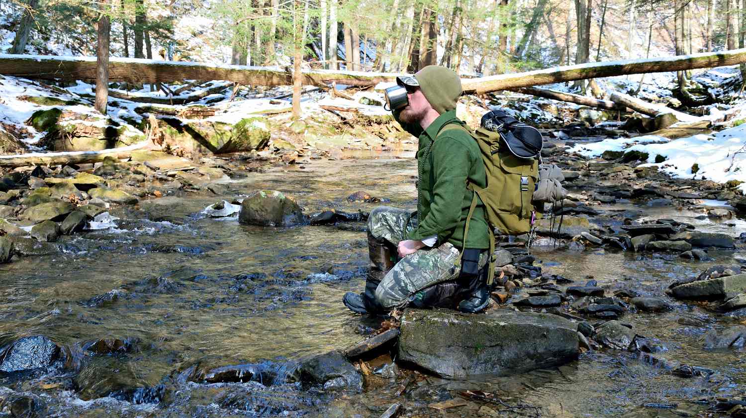 Man along a mountain stream in the forest | Outdoor Survival Skills For The True Outdoorsman | Featured