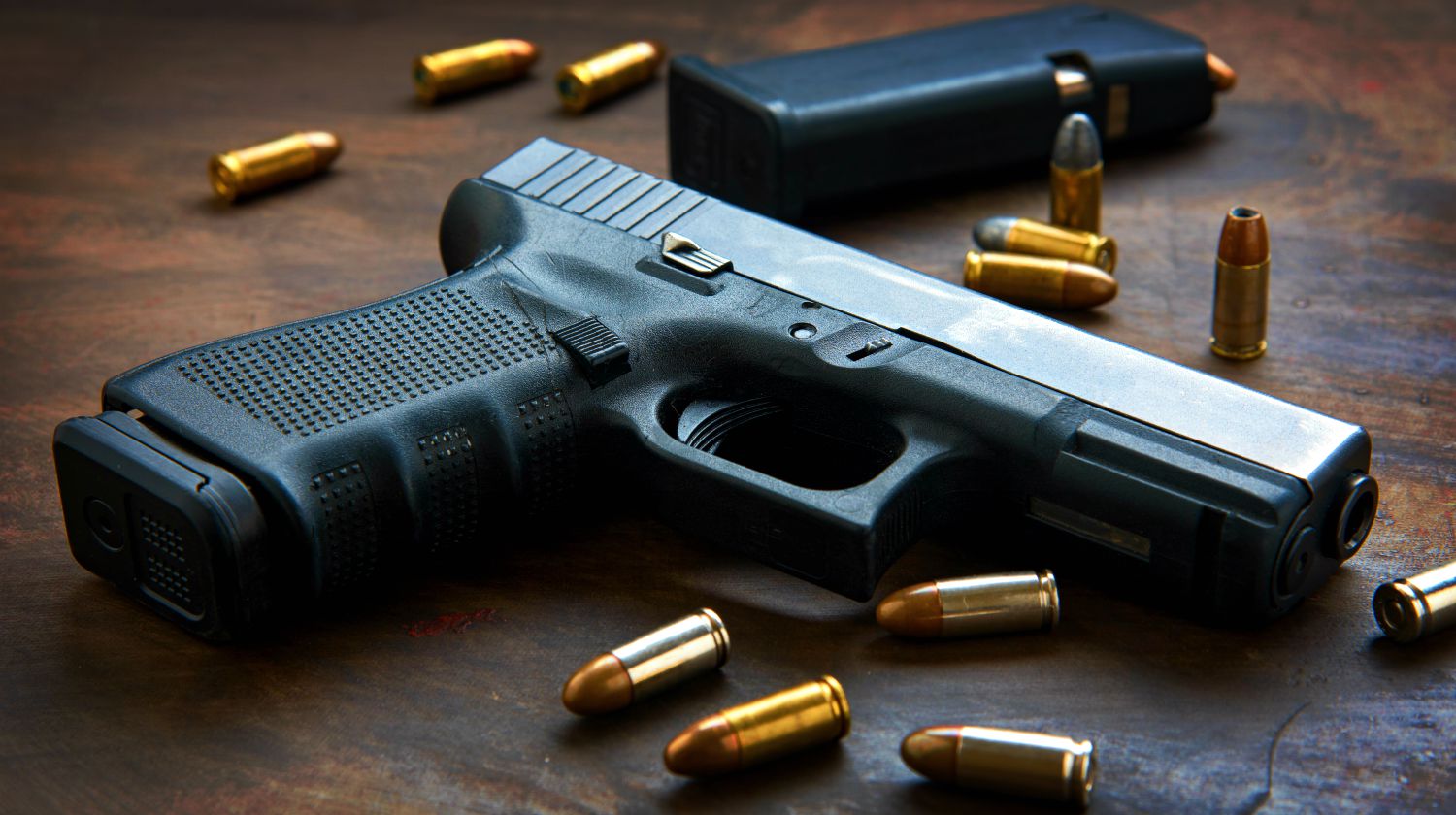 Feature | Gun with ammunition on wooden background | Modern Shooter: Is .32 ACP Sufficient?