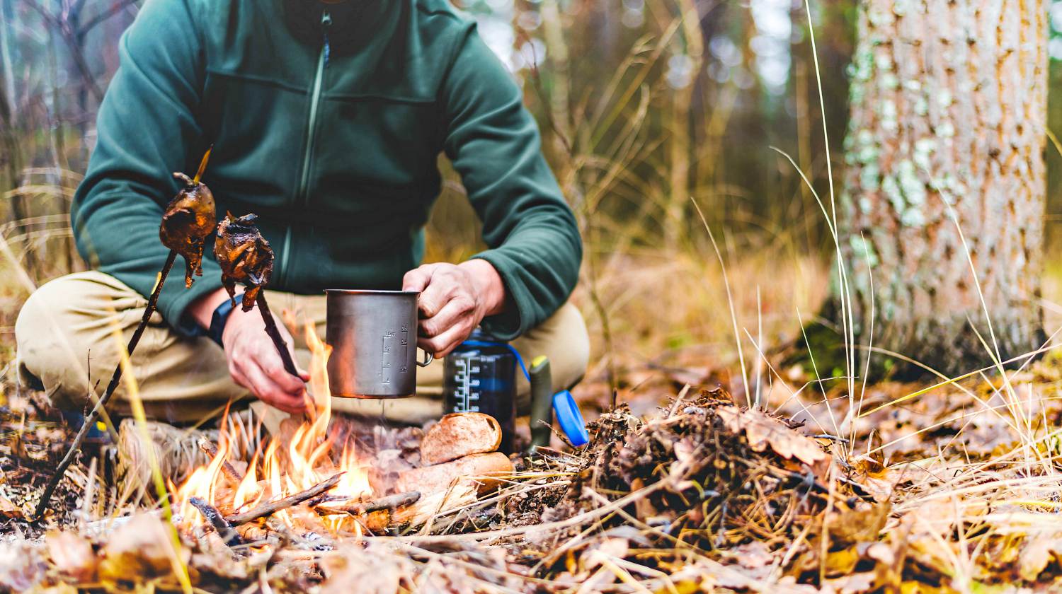Feature | Hunter at rest pours from a plastic bottle in a titanium mug of water | Top Survival Skills | Learn Now, Survive Later