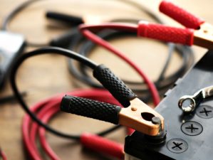 A car battery with red and black battery jumper Cables with copper clamps attached to the terminals | How To Revive Car Batteries: Don't Throw Dead Batteries Just Yet | Featured