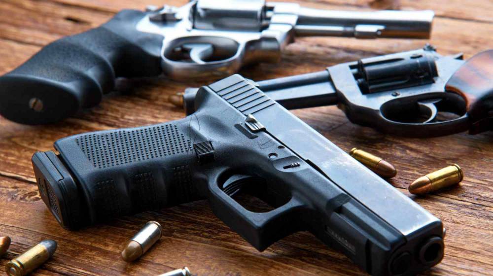 Feature | Gun with ammunition on wooden background | Must Have Pistols | 36 Must Own Handguns