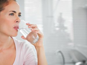 Feature | Pensive blond woman drinking water in her kitchen | Ways To Get Clean Drinking Water In An Emergency