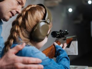pleasant-cheerful-man-helping-his-daughter | real guns for kids | Featured