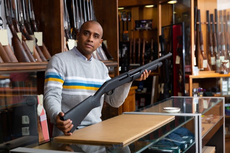 gun-shop-salesman-demonstrates-pump-action home defense pump shotgun