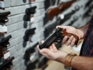 man-holds-handgun-gun-shop investing in guns | Featured