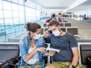 COVID-19 worldwide borders closures. Couple with face mask stuck in airport terminal after being denied entry to other countries-Coronavirus State Restrictions-ss-featured