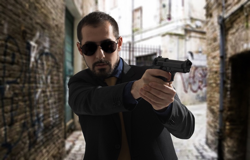 Man aiming a gun in a dark ghetto street | handgun grip