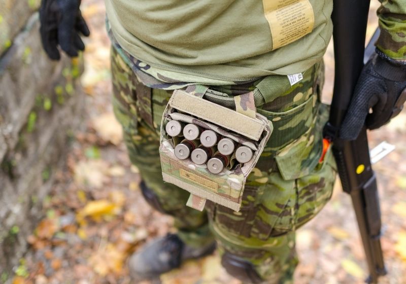 Person in green camouflage print pants carrying shotgun shells | dove hunting choke
