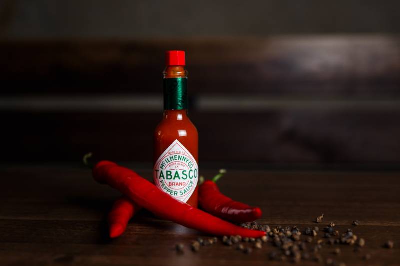 Horizontal photo of a tabasco sauce bottle with red chilli and black peppers how to make pepper spray SS 1