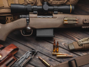 Modern bolted carbine and cartridges for it on a dark wooden table | Best Survival Rifles You Should Own | featured