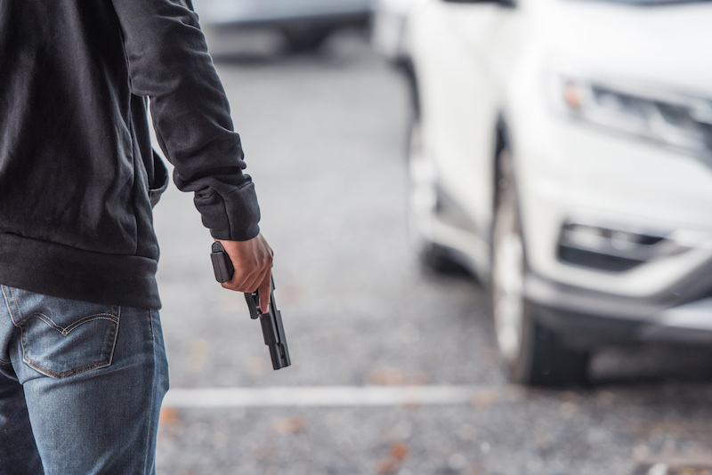 Back view of man holding a gun in car park | survival rifle 22 410