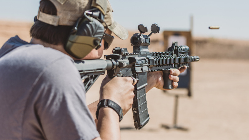 Man shooting rifle on desert range medium shot shell ejecting | henry survival rifle