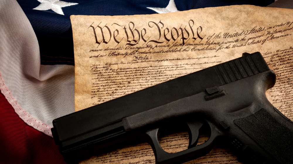 The second amendment and gun control in america concept with a handgun and the american constitution on the USA flag with close up on the we the people-Second Amendment Sanctuary-ss-featured