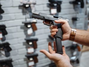 man-choosing-new-handgun-gun-shop | Gun Control And Owner Rights Podcast [LISTEN] | Featured