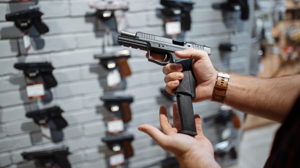 man-choosing-new-handgun-gun-shop | Gun Control And Owner Rights Podcast [LISTEN] | Featured