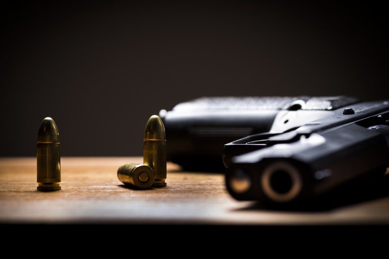 Black Handgun and bullets on a wooden background | home defense handguns