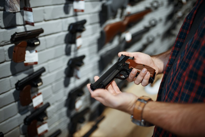Man holds handgun in gun shop | home defense handguns