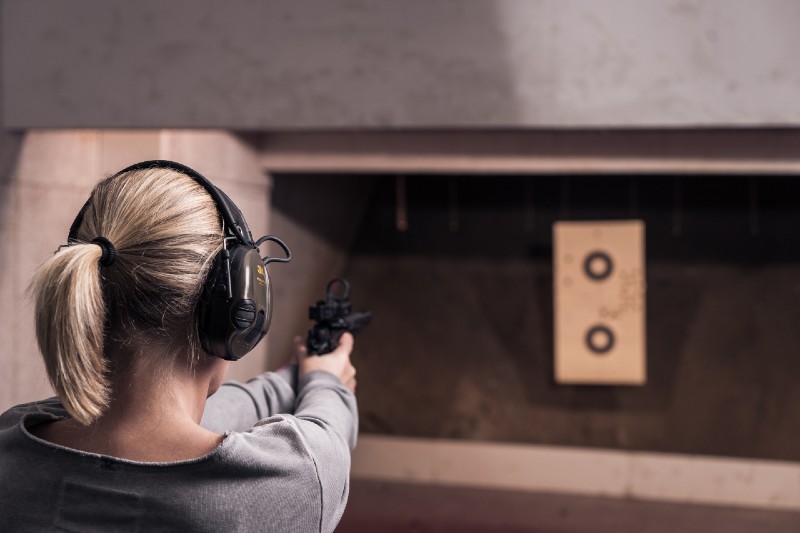 Woman with pistol weapon in hands at shooting range with target | 9mm vs .40 S&W vs .45