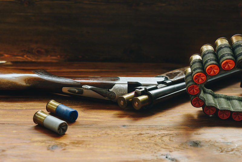 Shotgun and hunting cartridges on wooden table | best home defense shotgun ammo