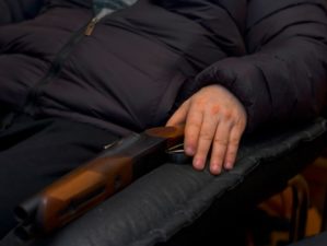 A man sitting with a shotgun in armchair, concept of home self defence | Features of a Home-Defense Shotgun