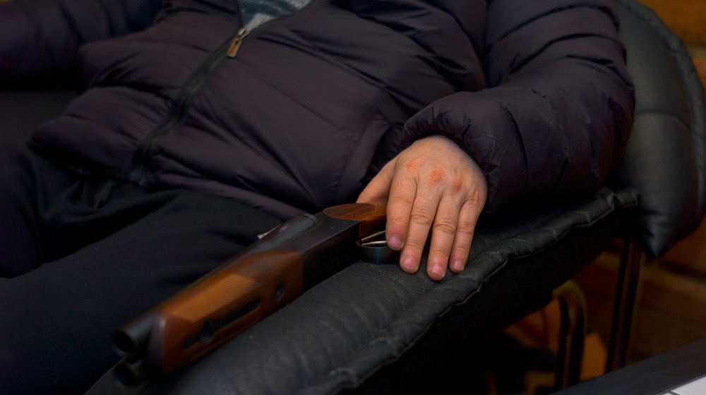 A man sitting with a shotgun in armchair, concept of home self defence | Features of a Home-Defense Shotgun