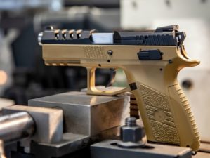 A modern pistol with a beige grip on a work table | Is the FN 509 Gun For You?| Featured