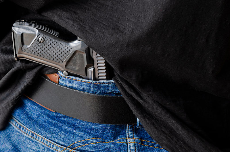 A person is hiding a handgun under the denim belt | bersa thunder 380 price