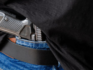 A person is hiding a handgun under the denim belt | Best Handgun for Beginners | featured