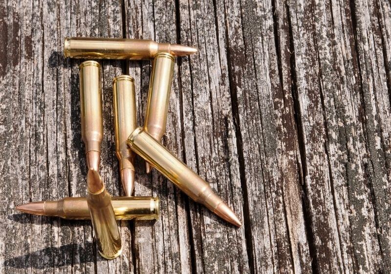 Seven .223 rifle bullets together on a wooden background Keltec p50 SS