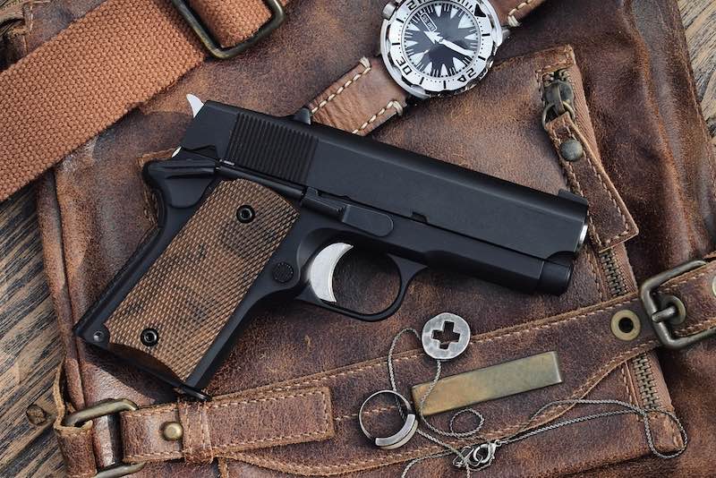 Small black gun (compact handgun) lying over a Leather handbag | pretty guns for females