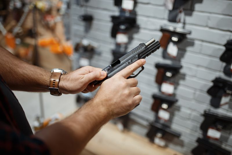 man-choosing-new-handgun-gun-shop | investing in guns
