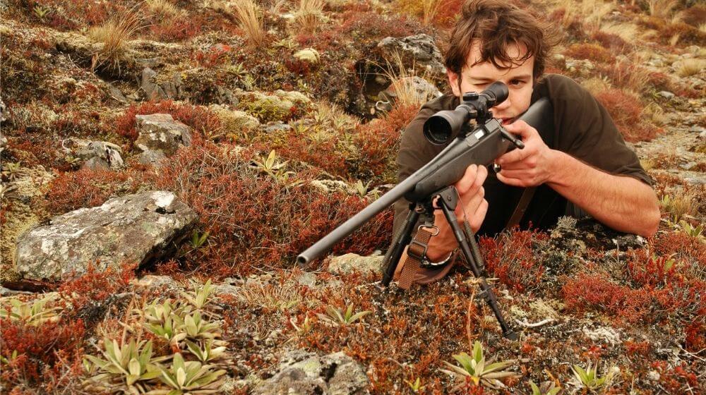 Hunter in alpine tussock aiming rifle | How to aim a rifle | Featured