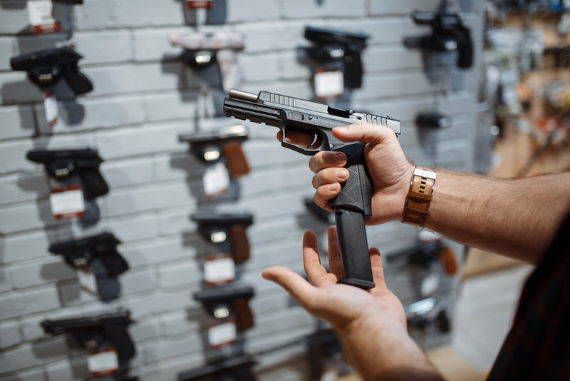 Man choosing new handgun in gun shop | budget pistols