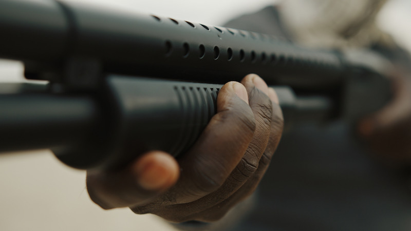 Afro-American man reloads pump action shotgun | sawed off double barrel shotgun