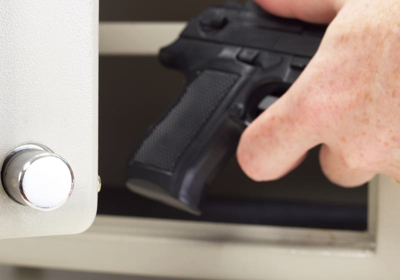 Person putting firearm in gun safe | best gun safe