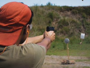 man in brown t-shirt and ref knit cap | How Should You Hold a Handgun for Maximum Accuracy | Featured